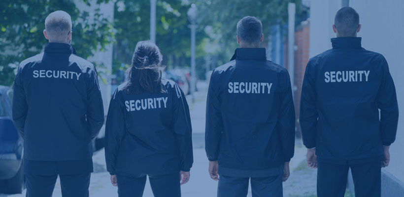 Four security guards facing away from camera. 