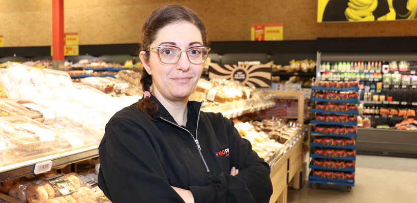 Union Member Sara smiles at the camera with her arms crossed while working in the No Frills bakery department.